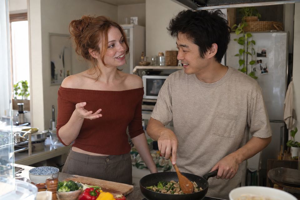 アパートのキッチンで料理しながら話す日本人の夫と外国人の妻